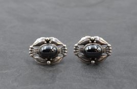 A pair of silver stud earrings by Georg Jensen having central hematite cabouchons in moulded open
