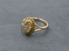 A Victorian/Edwardian yellow metal ring stamped 15ct having a trilogy of diamonds in an oval panel