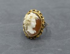 A conch shell cameo ring depicting a bacchanalian maiden in profile in a collared mount on a