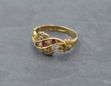 An Edwardian dress ring of shaped band form having inset seed pearls, diamond and ruby chips on an