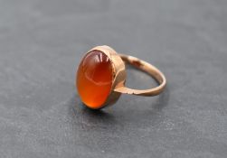 A 9ct rose gold dress ring having an oval orange agate cabochon in a collared mount, size O & approx
