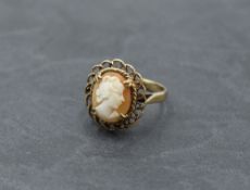 A cameo ring depicting a maiden in profile in a decorative mount on a yellow metal loop stamped 9ct,