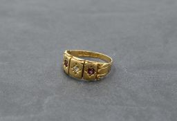 A Victorian 18ct gold band ring having an inset diamond flanked by two rubies with moulded detail to
