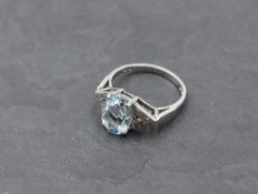 An aqua marine dress ring having an oval stone within diamond set Art Deco style shoulders on an