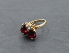 A dress ring having two ruby style teardrop stones in claw set heart mounts with a clear paste stone