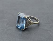 An oversized dress ring having a rectangular cut blue topaz in a four claw basket mount to