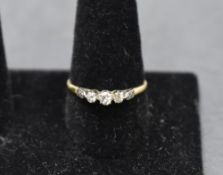 A diamond trilogy ring, total approx 0.250ct in claw set raised mount to moulded shoulders on a