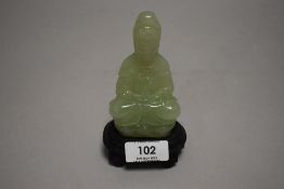 A light green jade or nephrite figure statue of a seated Tibetan Buddha sat on lotus leaf with