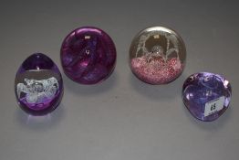 Four art glass paper weights in pink and purple hues including Caithness etc