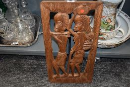 A mid century tribal carved hard wood panel depicting ethnic villagers