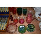 A selection of cranberry glass wares and two Mdina art glass paper weights