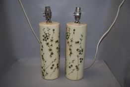 A pair of modern side or table lamps being hand decorated with leaf and berries