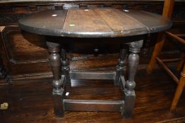 An oak side table in a dark stain having fold out and swivel top