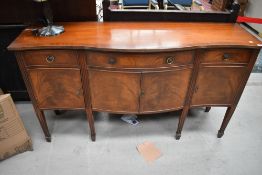 A bow fronted side board having cupboard and drawer storage