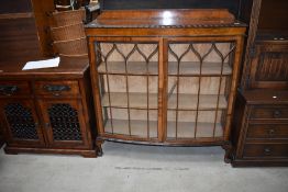 An Edwardian bow fronted book case having open glass front with shaped beading