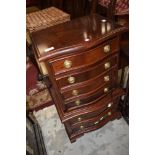 A reproduction hardwood small serpentine chest on chest