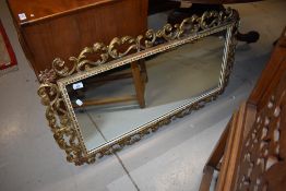 A reproduction gilt effect wall mirror having foliate frame