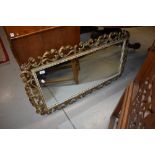 A reproduction gilt effect wall mirror having foliate frame