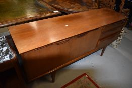 A vintage teak sideboard having three drawers and double cupboard on stylised legs, probably 1970s