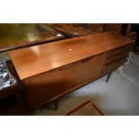 A vintage teak sideboard having three drawers and double cupboard on stylised legs, probably 1970s