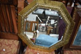 An arts and crafts hand worked octagonal mirror with brass frame and bevel edged glass