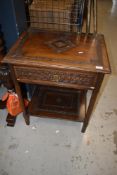 A late Victorian side table having part carved top, frieze drawer and undershelf