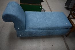 A modern ches long upholstered in a blue fabric with fold out seat for storage