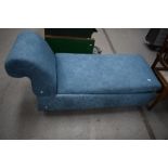 A modern ches long upholstered in a blue fabric with fold out seat for storage