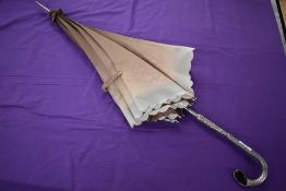 A dramatic 1950s umbrella having ornate metal handle with faux gemstone,and stunning floral lining