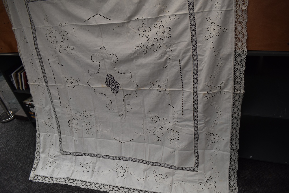 An antique white work linen bed throw with deep crotchet edging and cut work floral pattern.
