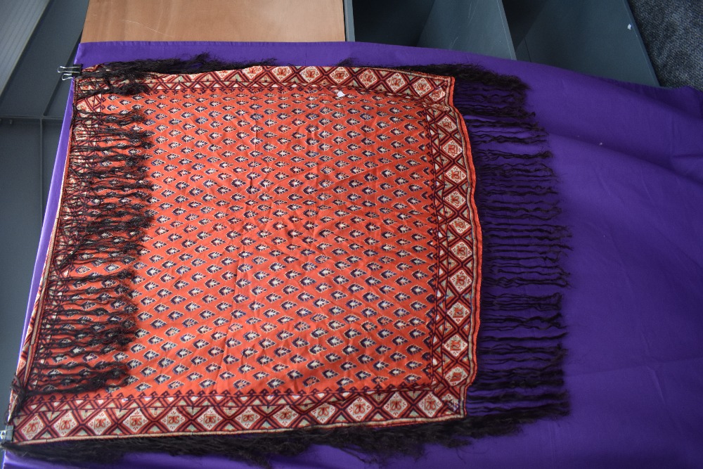 A Circa 1900s red silk shawl having deep fringing and green,burgundy and purple pattern.