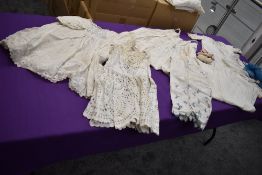A collection of antique childrens clothing including booties and dresses.
