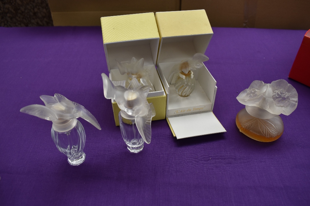 A collection of Nina Ricci perfume bottles, one having partial contents and the others empty, one