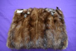 A mink fronted muff having heads attached with zip compartment to gathered reverse.