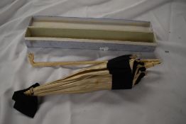A Victorian/Edwardian cream silk parasol with black grosgrain ribbon edging, having handle with
