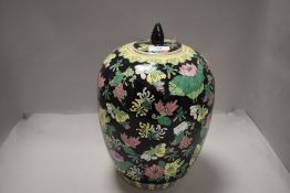 A Chinese ginger jar of large form in a famille noir glaze with lily and honey suckle design