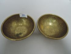 A pair of Islamic temple bowls in chase worked brass with Arabic designs