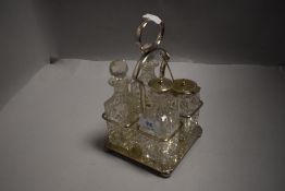 A sliver plate and cut glass four division cruet set, the base with unusual hand grasping fleur