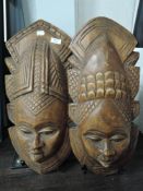 Two carved hardwood tribal masks, with pronounced features and elabrate headdress.