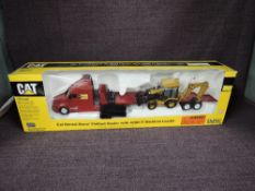 A Norscot 1:50 scale diecast, CAT Rental Store Flatbed Hauler with 420D IT Backhoe Loader, in