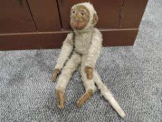 A Schuco style mohair Monkey having plastic eyes, felt face and ears stitched limbs with felt pads