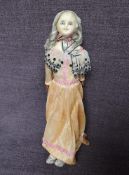 A mid 19th century Wax Headed Doll having grey hair and fixed open blue eyes in the Peddler style,