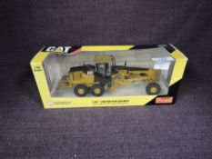 A Norscot 1:50 scale diecast, CAT 14M Motor Grader in yellow, in plastic packaging and in window