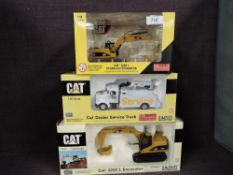 Three Norscot 1:50 scale diecasts, CAT 320CL Excavator in yellow, in polystyrene packaging and in