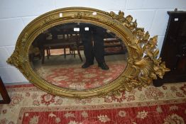 An Edwardian bevelled glass mirror having ornate floral gilt frame.