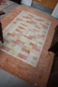 A modern carpet square having geometric terracotta and cream design 230 x 166 cm