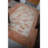 A modern carpet square having geometric terracotta and cream design 230 x 166 cm