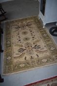 A wool or wool blend traditional style rug in cream,green and red tones with fringed edge, approx