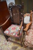 A late 19th or early 20th Century oak carver chair having carved crown to back, bergere panel, and