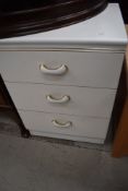 A white laminate three drawer bedside chest